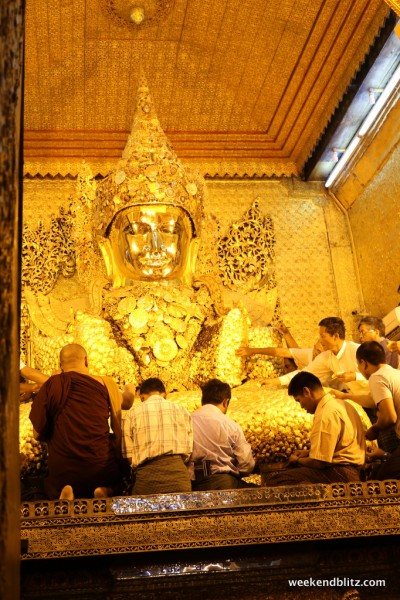 Men applying gold leaf to the Buddah at the M Pagoda